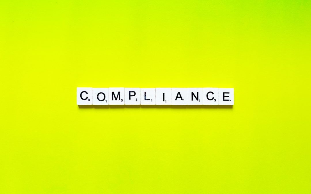 scrabble letter tiles that spell "compliance" with yellow background